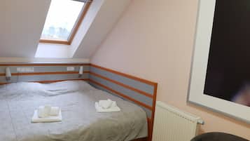 A bedroom with a single bed, a window, a radiator, and a power outlet on the wall.