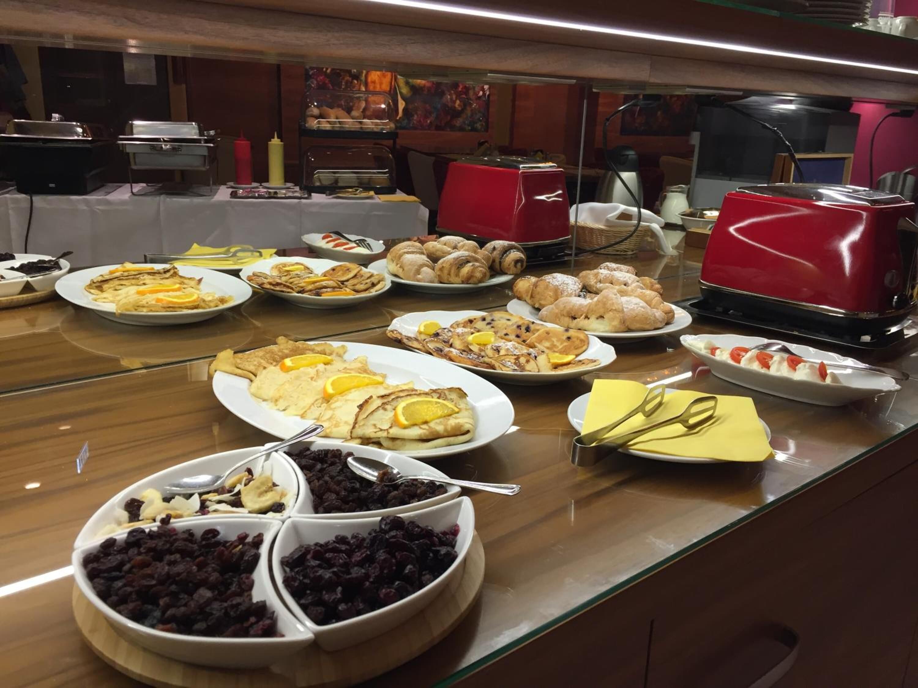A buffet with various dishes including pastries, fruits, and a selection of nuts.