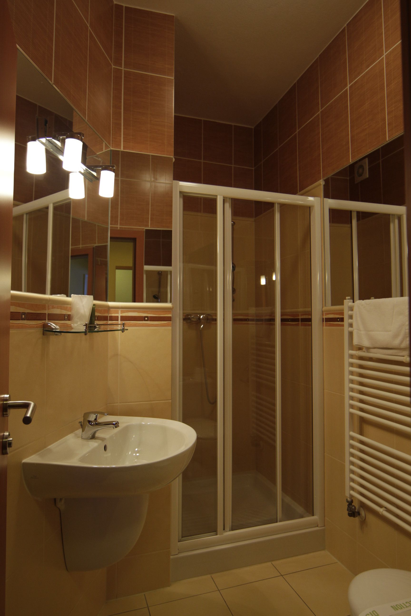 Ein Badezimmer mit Waschbecken, Spiegel, Dusche und Handtuchhalter.