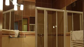Ein Badezimmer mit Waschbecken, Spiegel, Dusche und Handtuchhalter.