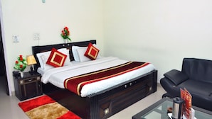 Quarto de hotel com cama, mesa de cabeceira, mesa de centro e sofá de couro preto.