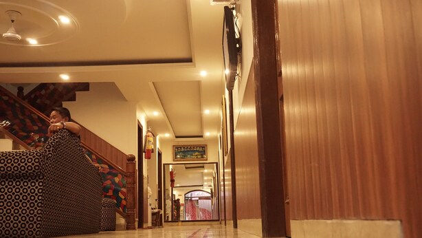 Um corredor de hotel com escadas de madeira, um sofá estampado e um quadro na parede.