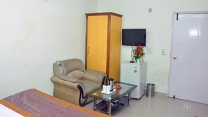 Quarto com cama, sofá, televisão na parede, armário e porta.
