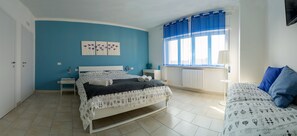 A bedroom with a bed, a bedside table, a window with curtains, and a wall with a floral artwork. - My Room in Trani (Trani)