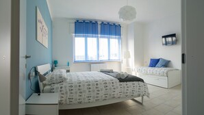 A bedroom with a large bed, a smaller bed, a desk, and a window with blue curtains. - My Room in Trani (Trani)