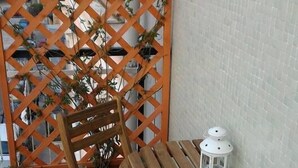 A wooden outdoor table with a chair, a white lantern, and a wooden lattice structure with plants. - My Room in Trani (Trani)