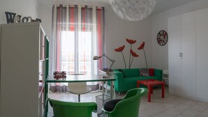 A modern living room with a glass dining table, green chairs, a red coffee table, a green sofa, and a white wardrobe. - My Room in Trani (Trani)