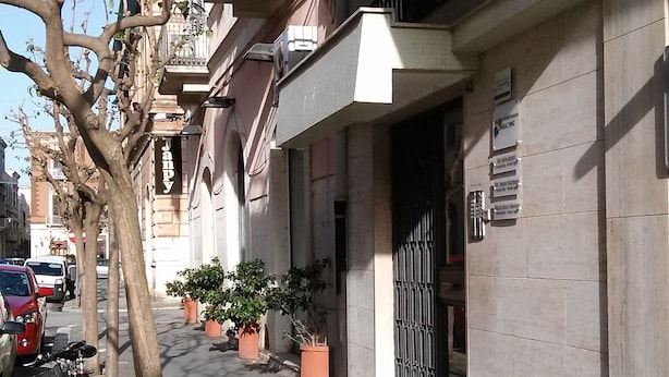 A narrow urban street with parked cars and potted plants lining the sidewalk. - My Room in Trani (Trani)