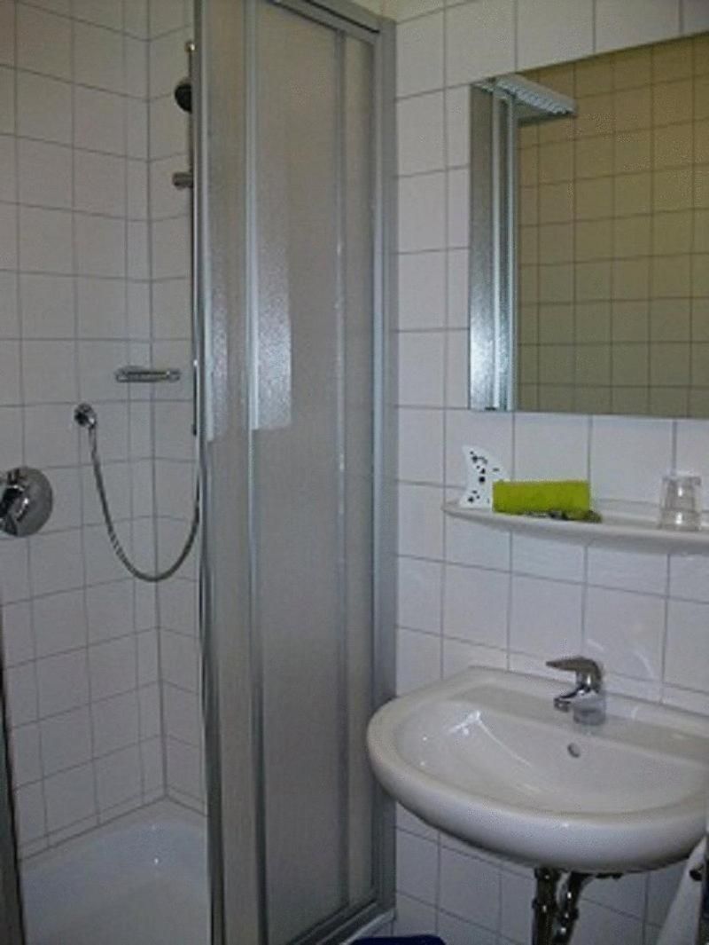 A bathroom with a shower enclosure, a sink, and a mirror above the sink.