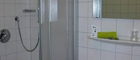 A bathroom with a shower enclosure, a sink, and a mirror above the sink.