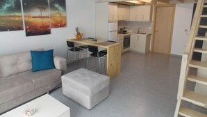 Un apartamento moderno con habitación en entrepiso, kitchenette, comedor y sala de estar.