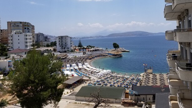 Vista costera con playa, sombrillas y edificios.