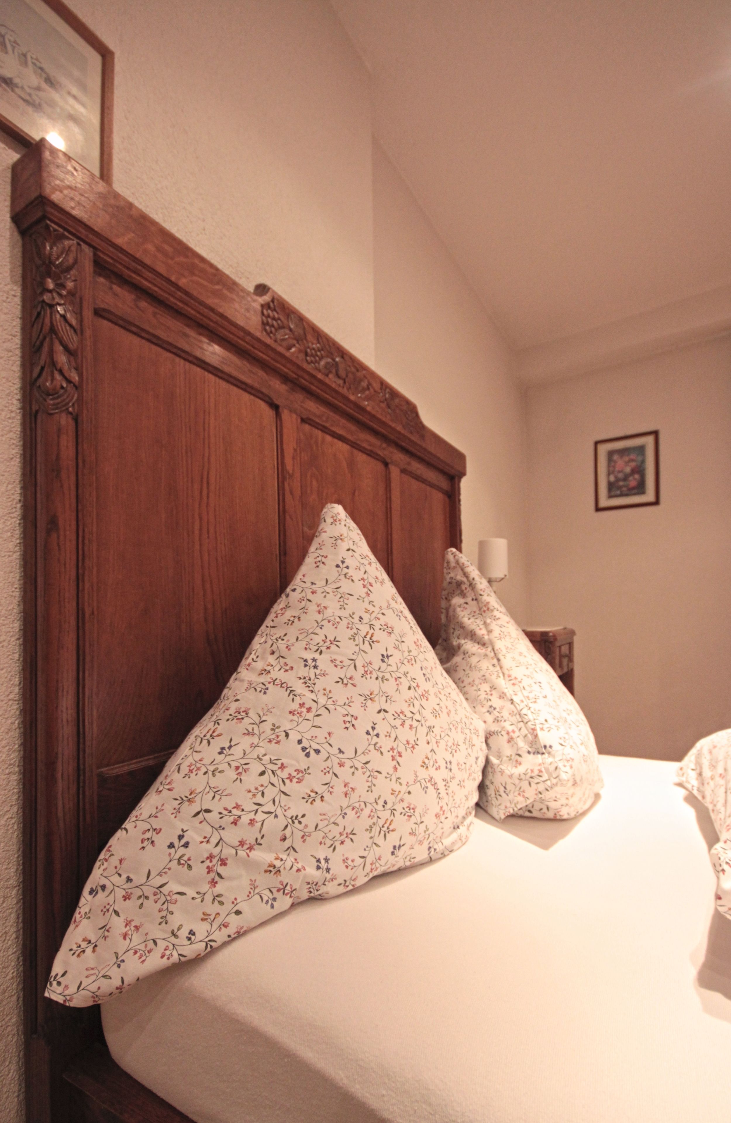 A bed with floral-patterned pillows and a wooden headboard.