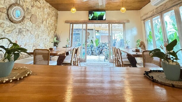 A spacious dining area with a wooden table, stone wall, and ceiling fan. - Lavella Villa's (Kuta)