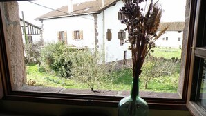 A window with a vase of dried flowers on a stone ledge. - Posada Elbete (Baztan)