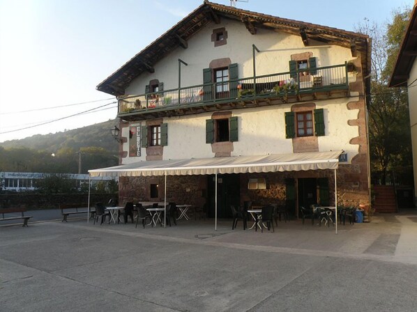 A two-story building with a balcony, outdoor seating area, and a sign that reads "EL BATE".