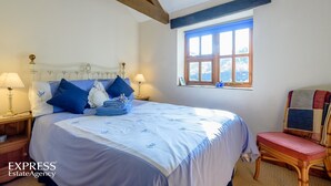 A bedroom with a bed, two bedside tables, a window, and a chair. - Highgrove Barns (Craven Arms)