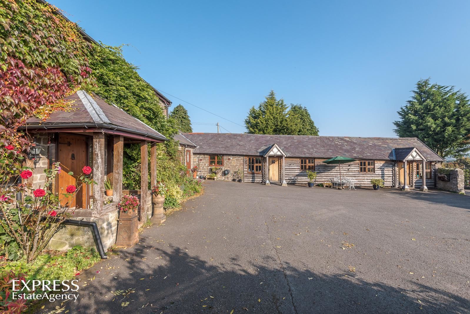 Ein traditionelles Steinhaus mit einer überdachten Veranda und einer breiten Auffahrt.