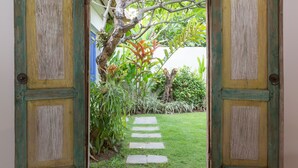 Una puerta de madera abierta que da a un jardín con un sendero de piedra.