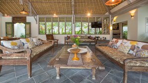 Un espacio interior amplio con techo alto, muebles de madera y ventanas grandes que dejan entrar luz natural.