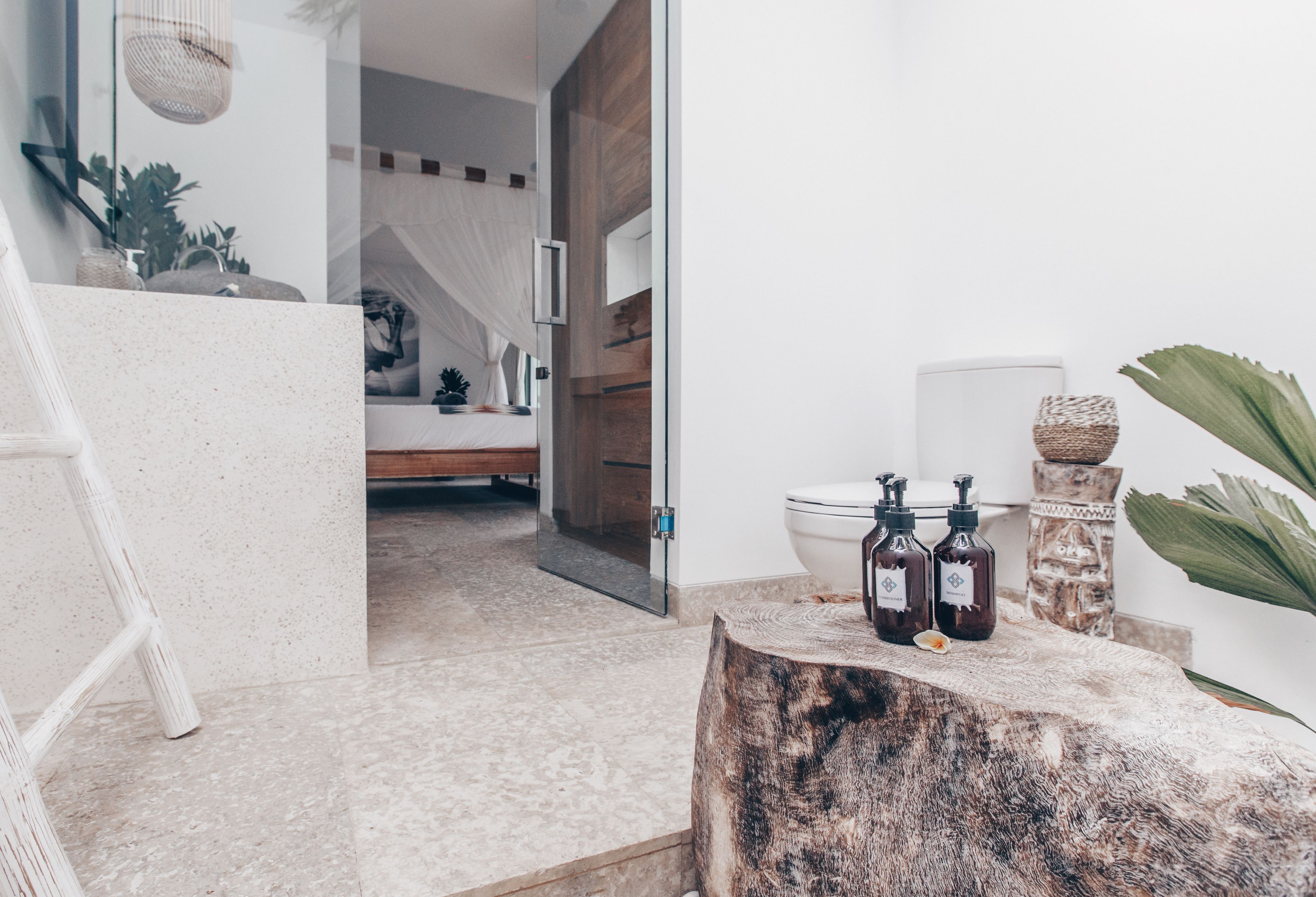 A modern bathroom with a wooden vanity, a mirror, and a sink. There is a staircase leading to another room.