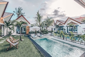 Una piscina al aire libre, sillones reclinables de piscina