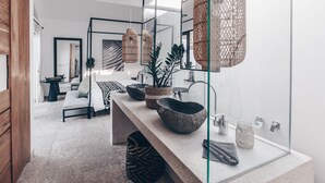 Un baño moderno con un espejo grande, un lavabo de piedra y una cabina de ducha de vidrio.