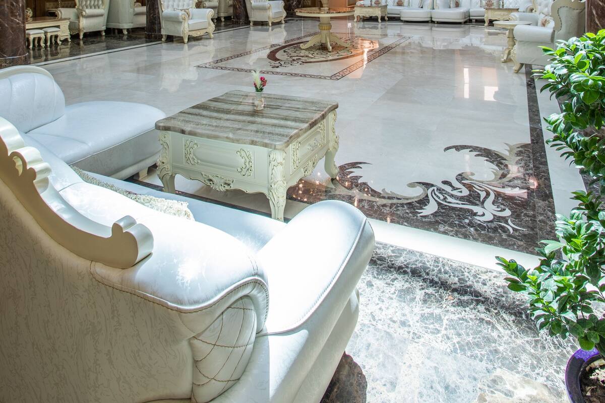 A spacious lobby with multiple seating areas, a grand chandelier, and a marble floor.