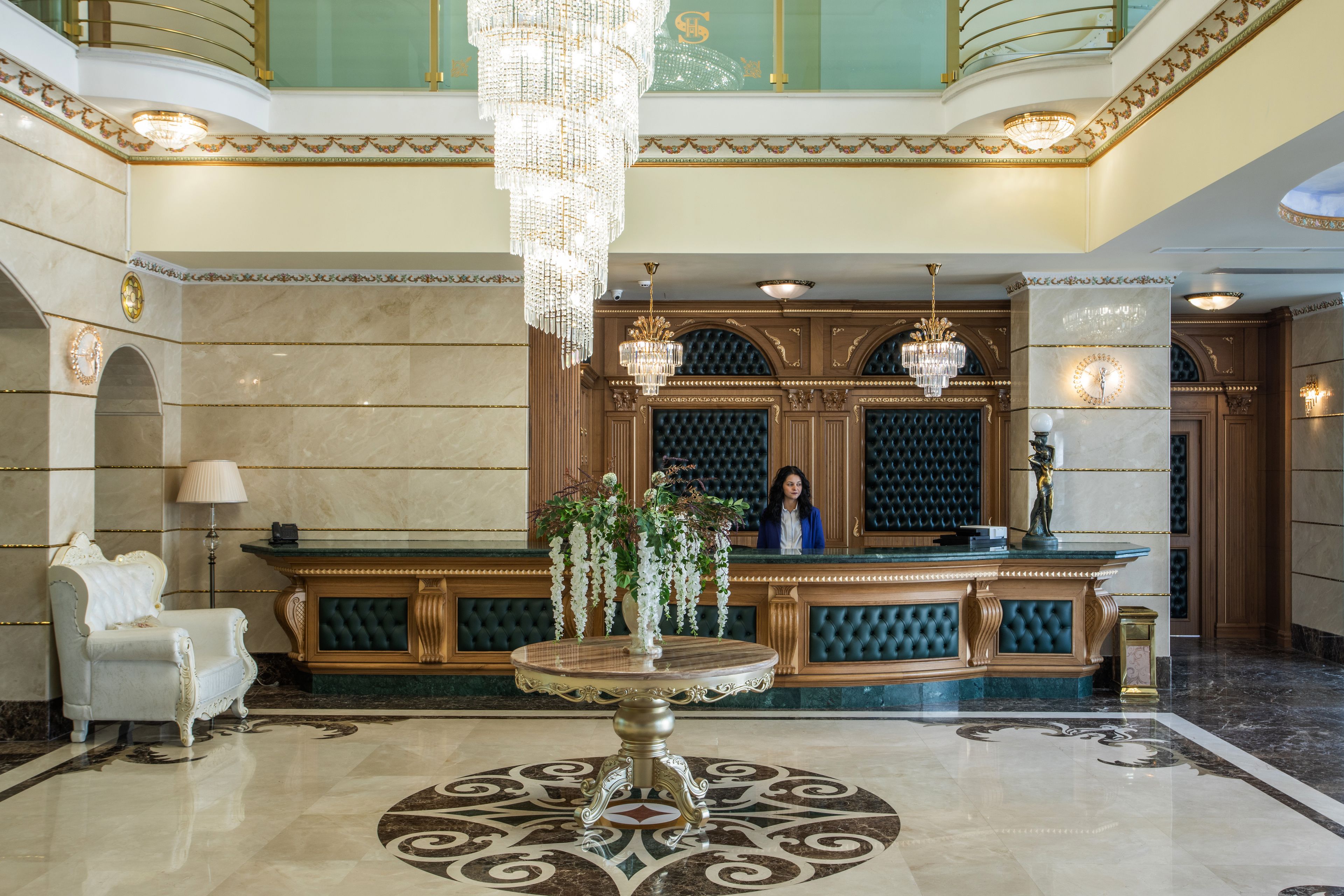 A luxurious lobby with a marble floor, a round table, and a reception desk.