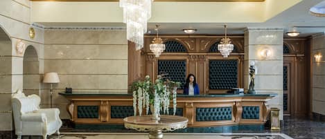 A luxurious lobby with a marble floor, a round table, and a reception desk.