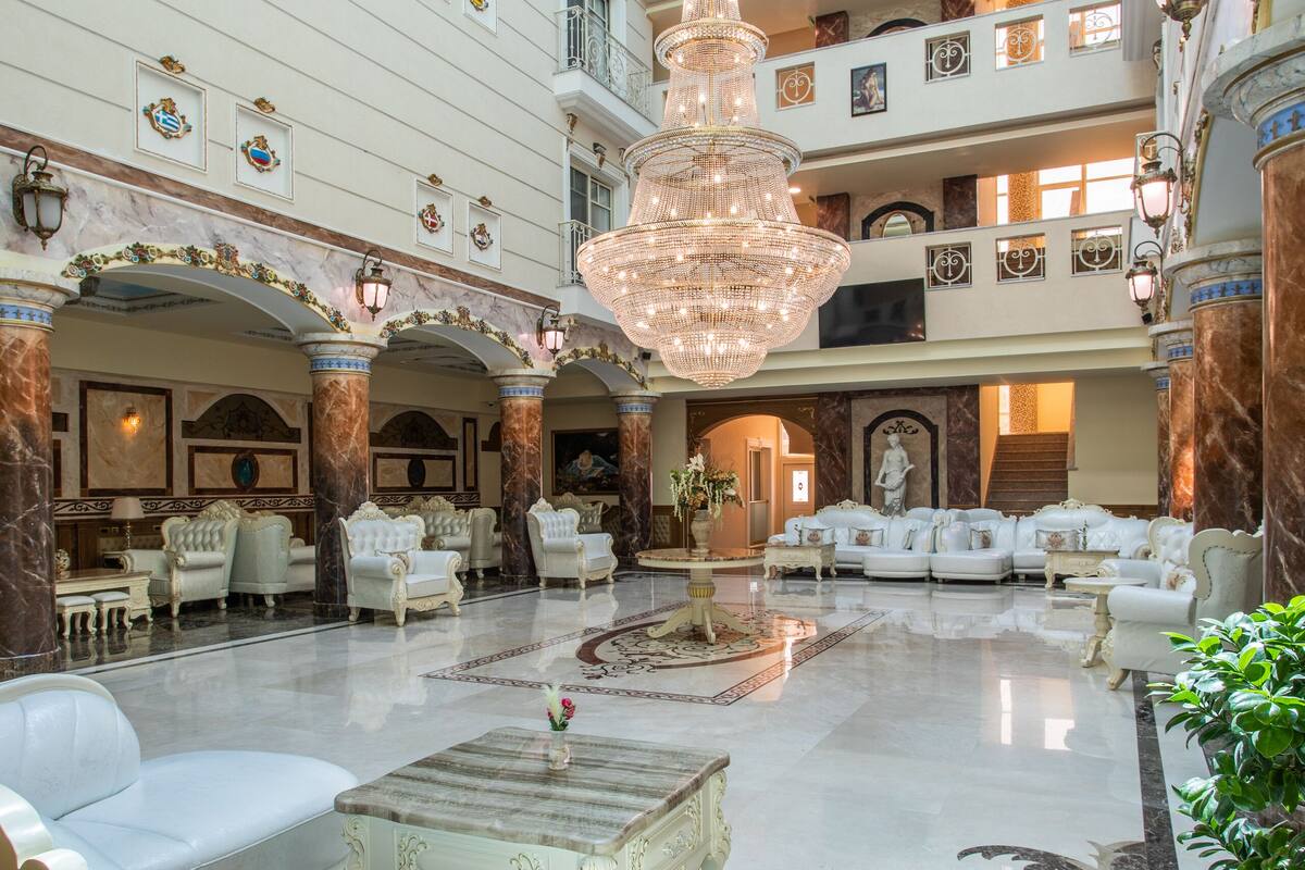 A spacious lobby with multiple seating areas, a grand chandelier, and a marble floor.