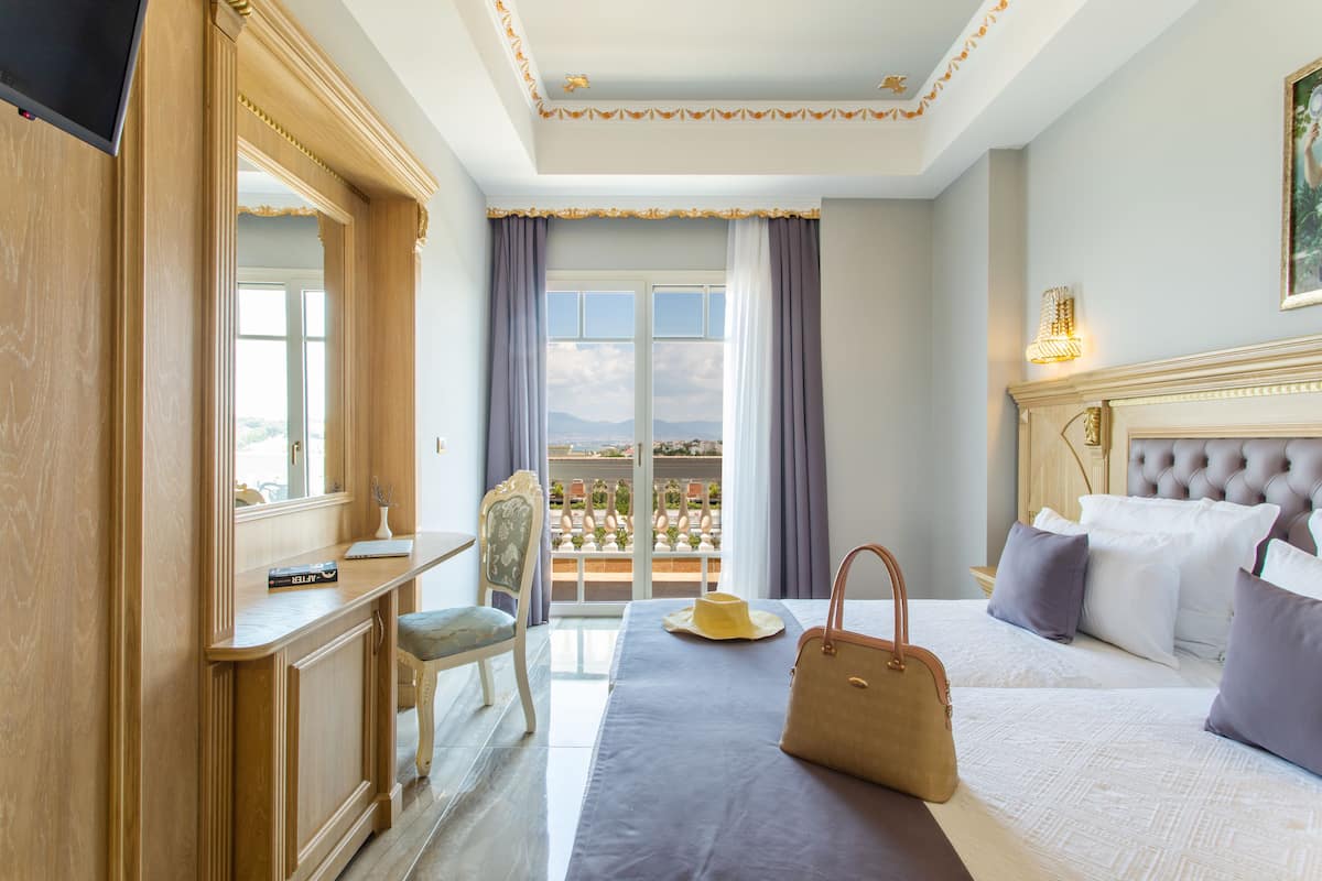 A hotel room with a large bed, a desk, a chair, and a view of the city.