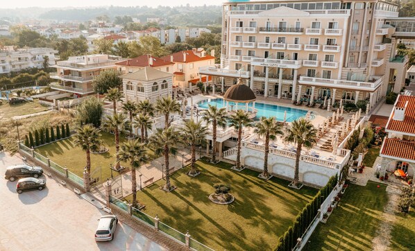 A resort with a swimming pool, palm trees, and a large building with balconies.