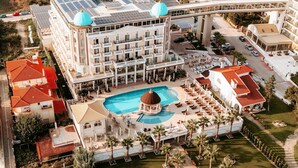 Um hotel com piscina central, várias varandas e estrutura em cúpula.