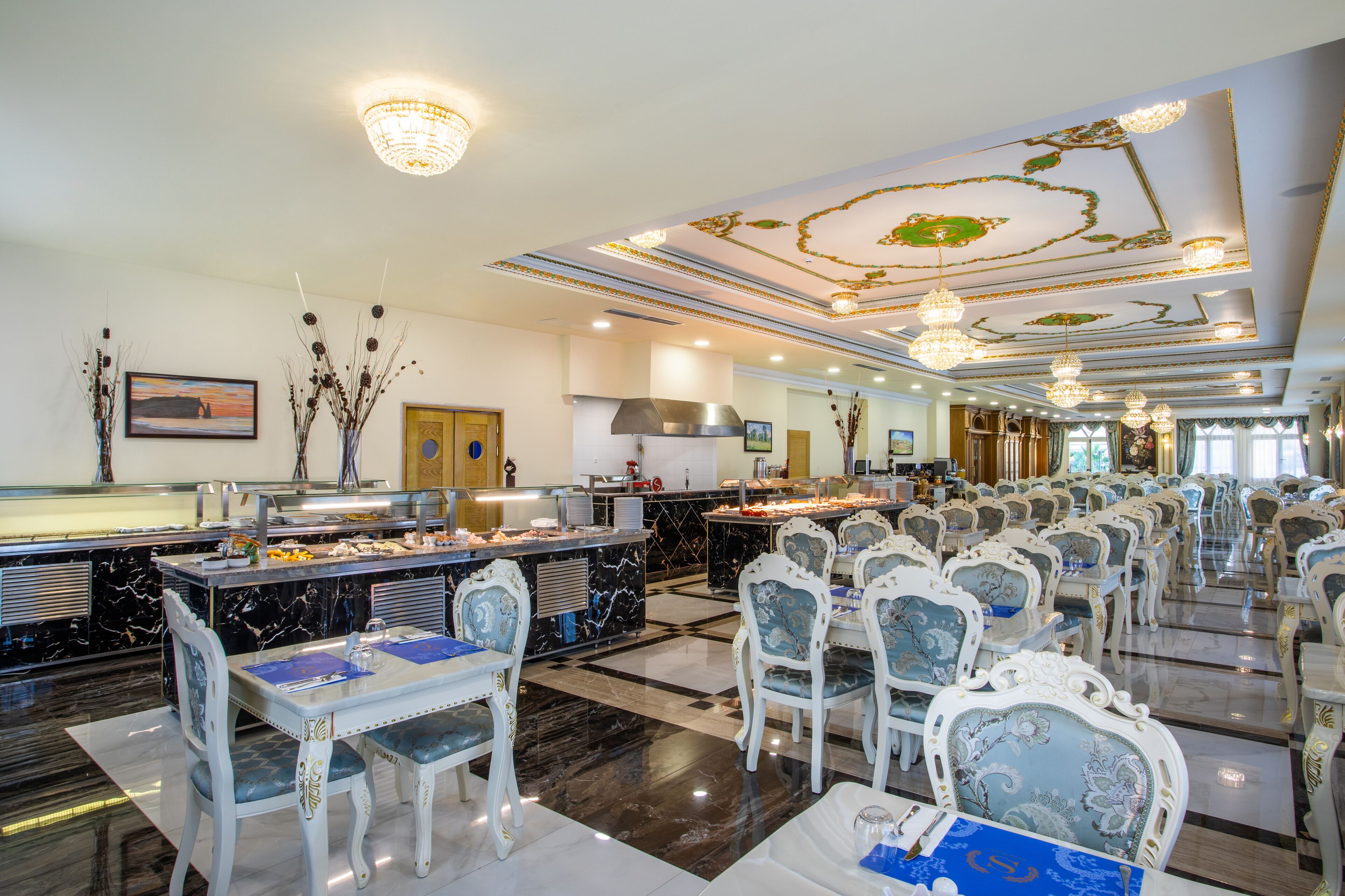A spacious banquet hall with marble flooring, ornate ceiling decorations, and rows of elegantly styled chairs.