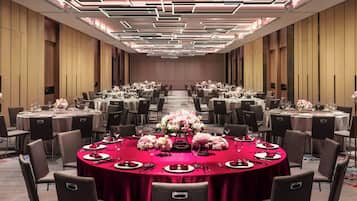 A conference room with round tables, chairs, and floral centerpieces.