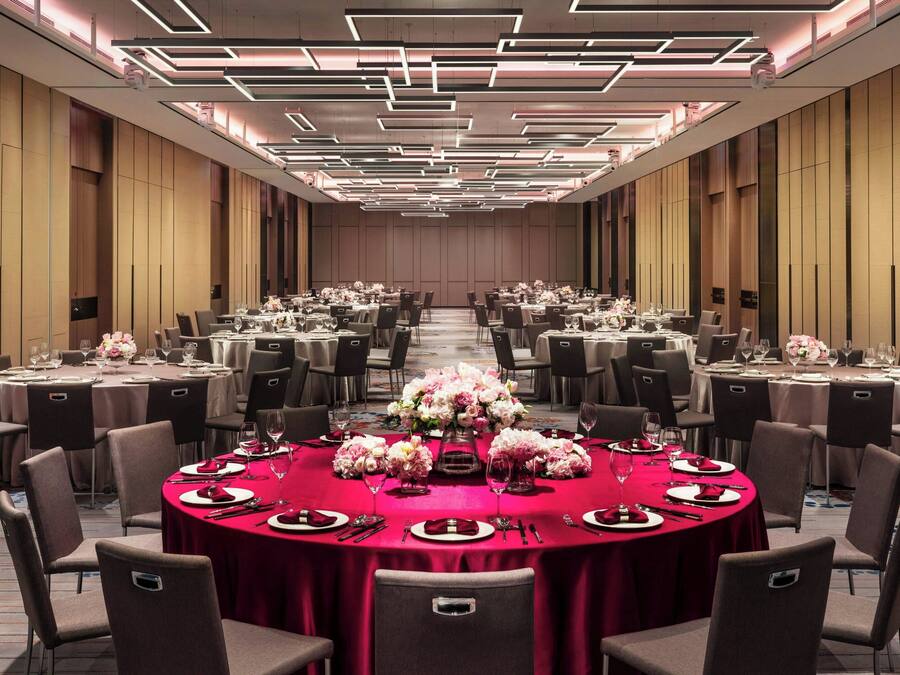 A conference room with round tables, chairs, and floral centerpieces.