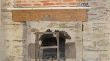 A stone fireplace with a wooden mantel and a brick roof.