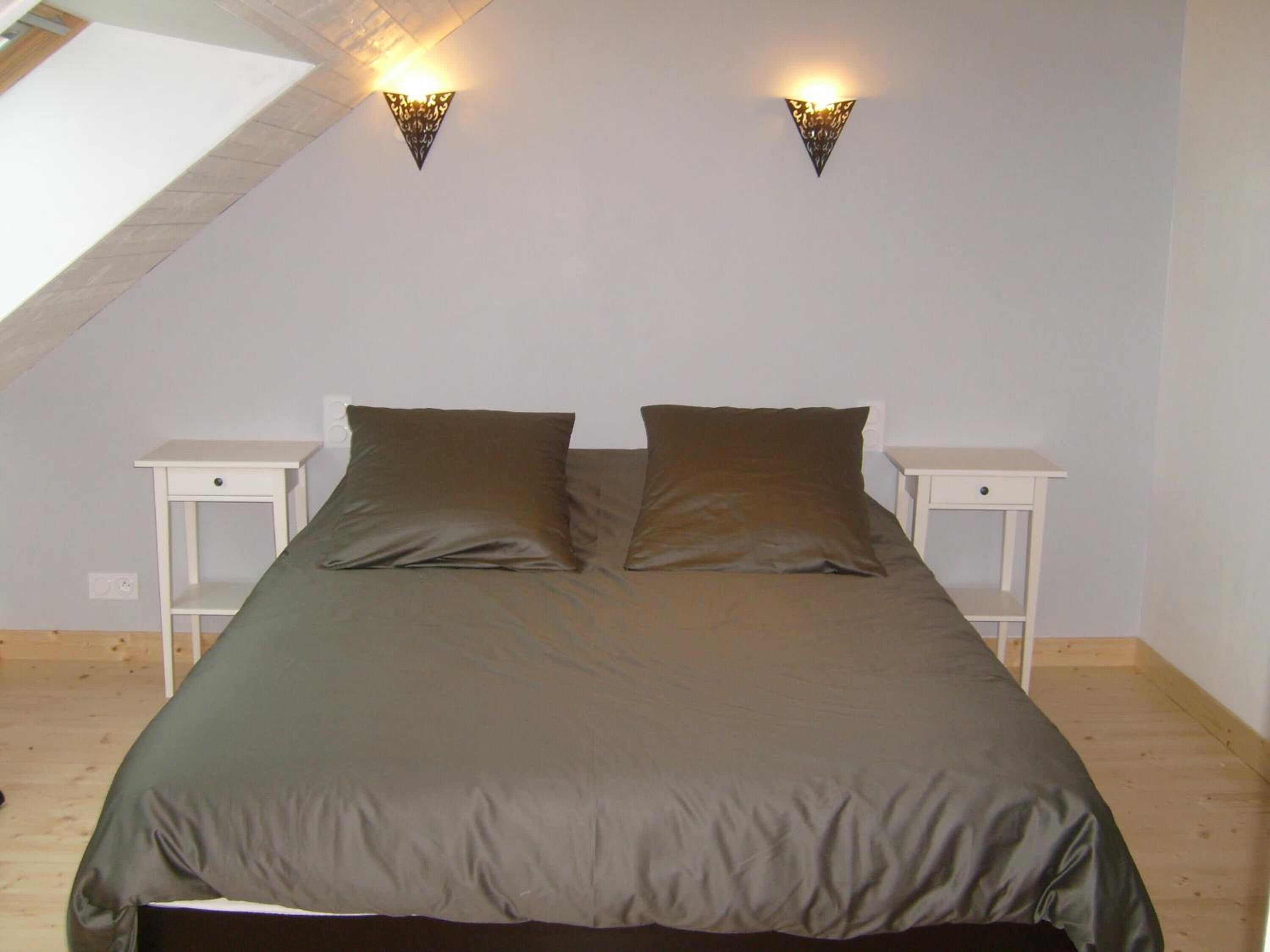 A bedroom with a bed, two nightstands, and two wall-mounted lights.