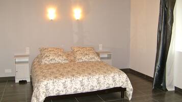Un dormitorio con una cama, dos mesitas de noche y dos luces fijadas a la pared.