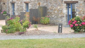 A stone building with a sloped roof, multiple doors, and a gravel pathway leading to the entrance. - Le Chêne Blanc (Plessé)