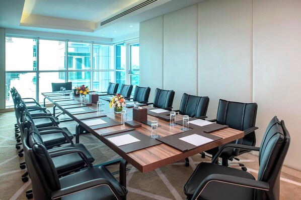 A conference room with a long table, multiple chairs, and a view of the city through large windows. - Four Points by Sheraton Sharjah (Sharjah)