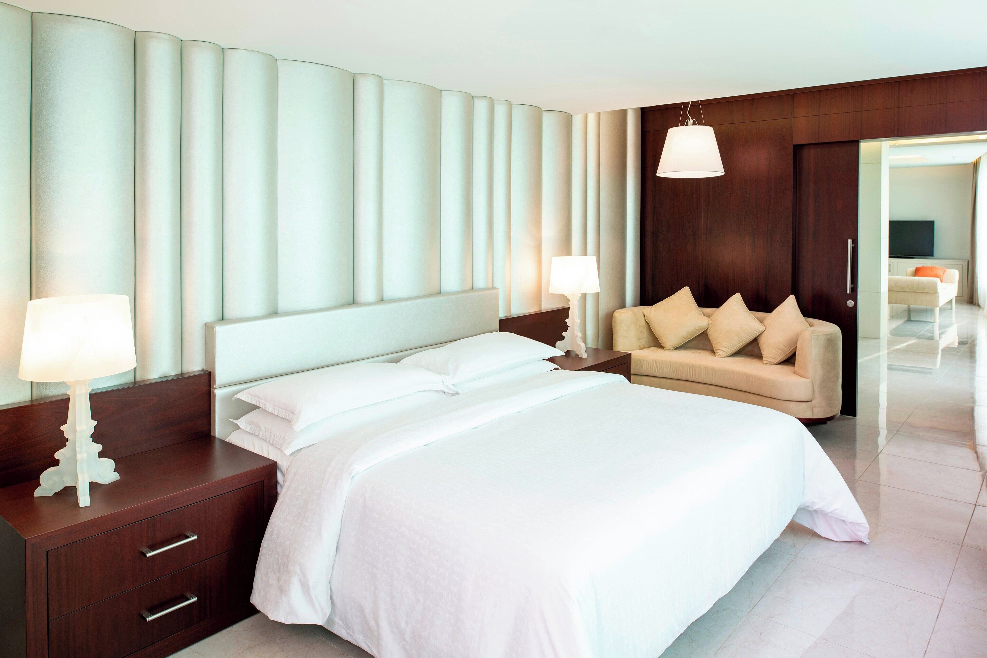Ein modernes Hotelzimmer mit einem großen Bett, einer Couch und einem Fernseher im Hintergrund.