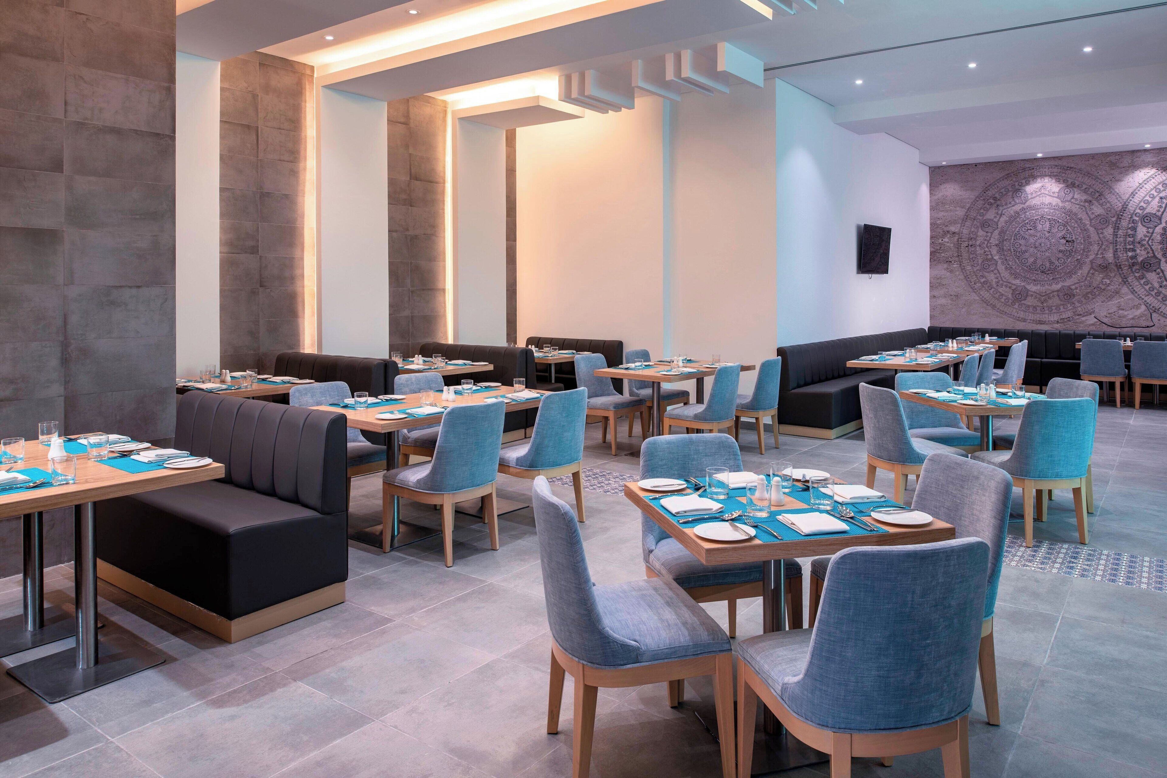 Un restaurante moderno con cabinas y mesas, algunas con cojines azules.