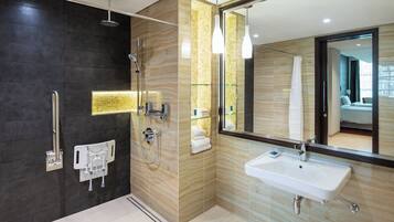 A modern bathroom with a glass shower enclosure, a large mirror, and a white sink.