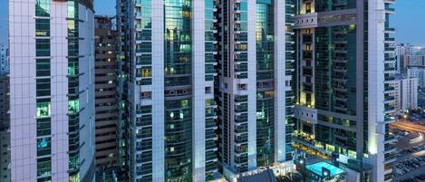 A high-rise hotel with multiple floors, balconies, and a pool area.