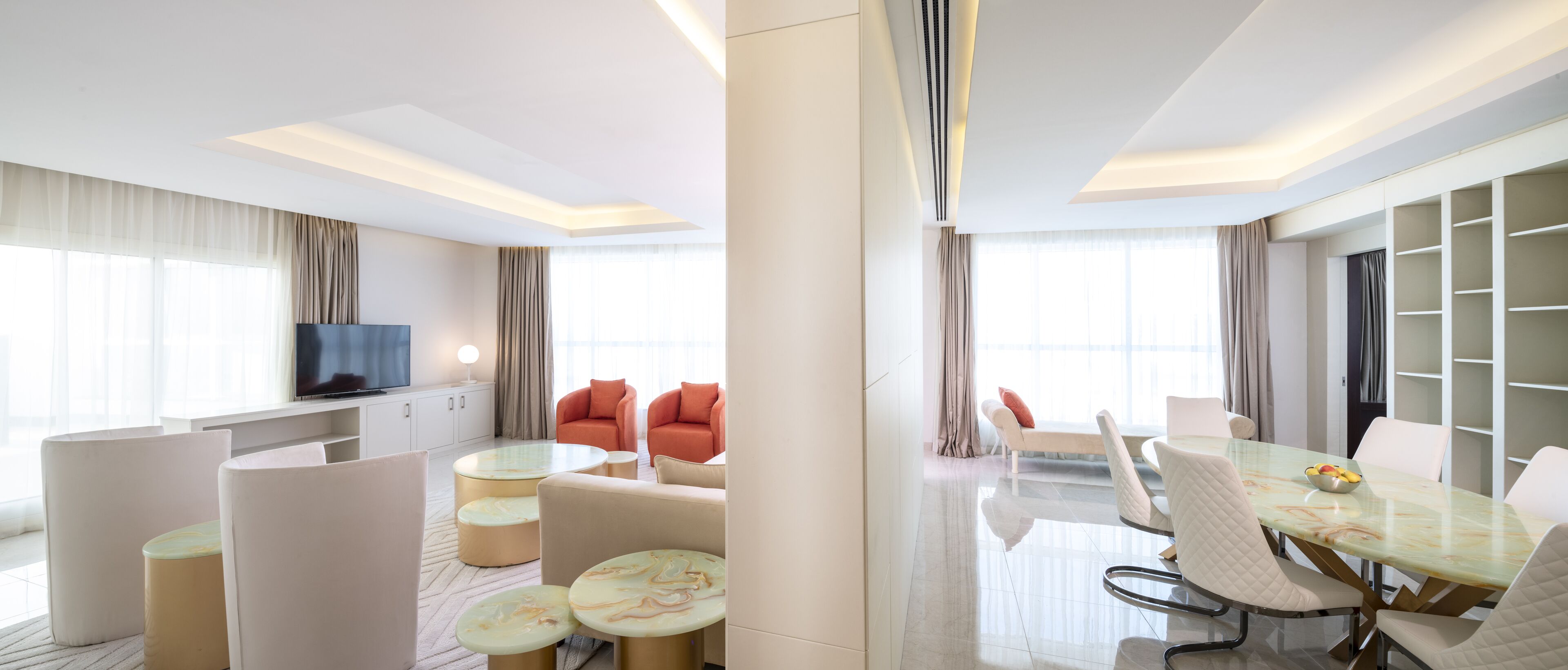 Una habitación de hotel moderna con sala de estar, mesa de comedor y televisor.