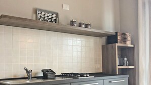 Eine moderne Küche mit grauen Schränken, einer schwarzen Arbeitsplatte und einer gefliesten Spritzschutzwand.