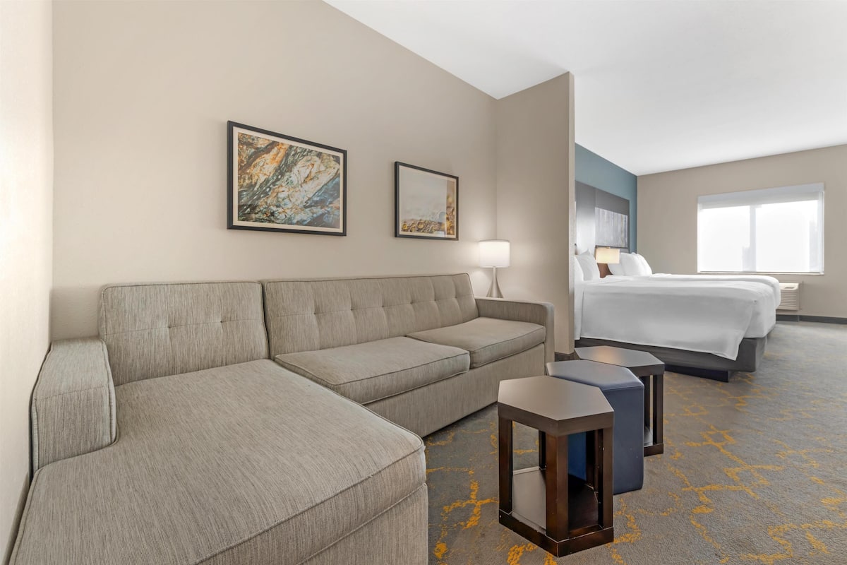 A hotel room with a sofa, a small table, a lamp, and a bed.