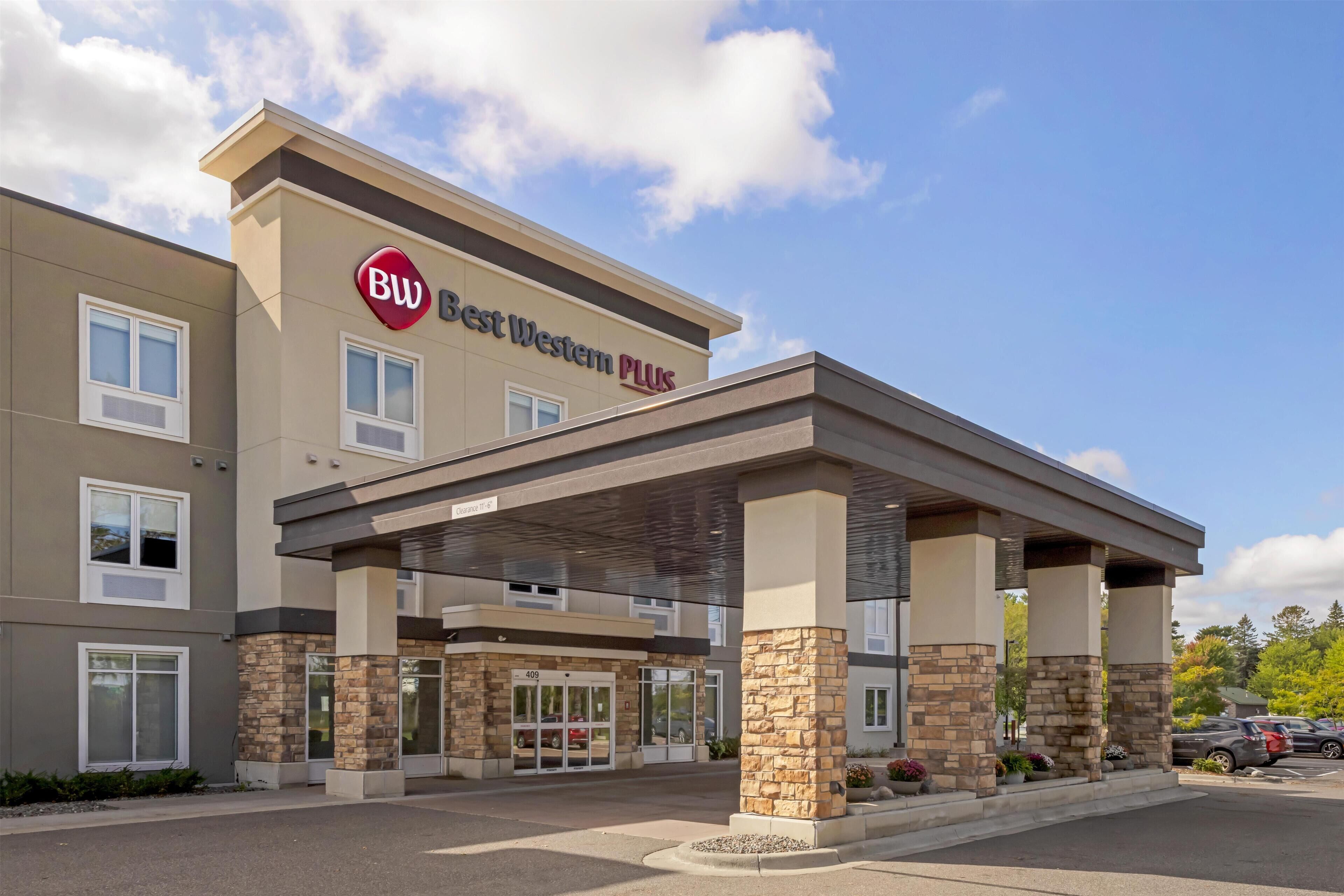 Een Best Western Plus hotel met een overdekte ingang, stenen zuilen en een parkeerplaats.